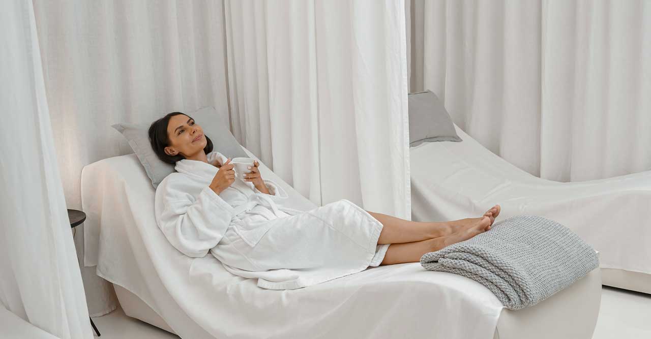 Woman relaxing in a white robe with a cup at a spa