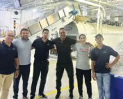 Elavo CEO Luis Aguilar poses for a photo with colleagues inside a commercial laundry facility.